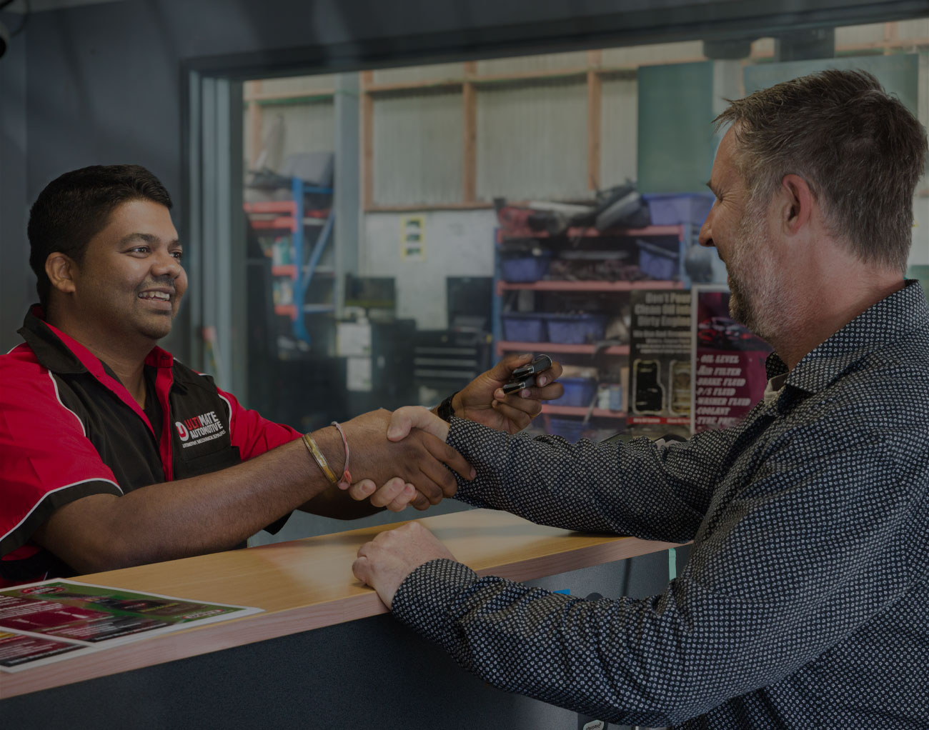 Ultimate Automotive staff member shaking hands with a customer at the service desk in Hamilton